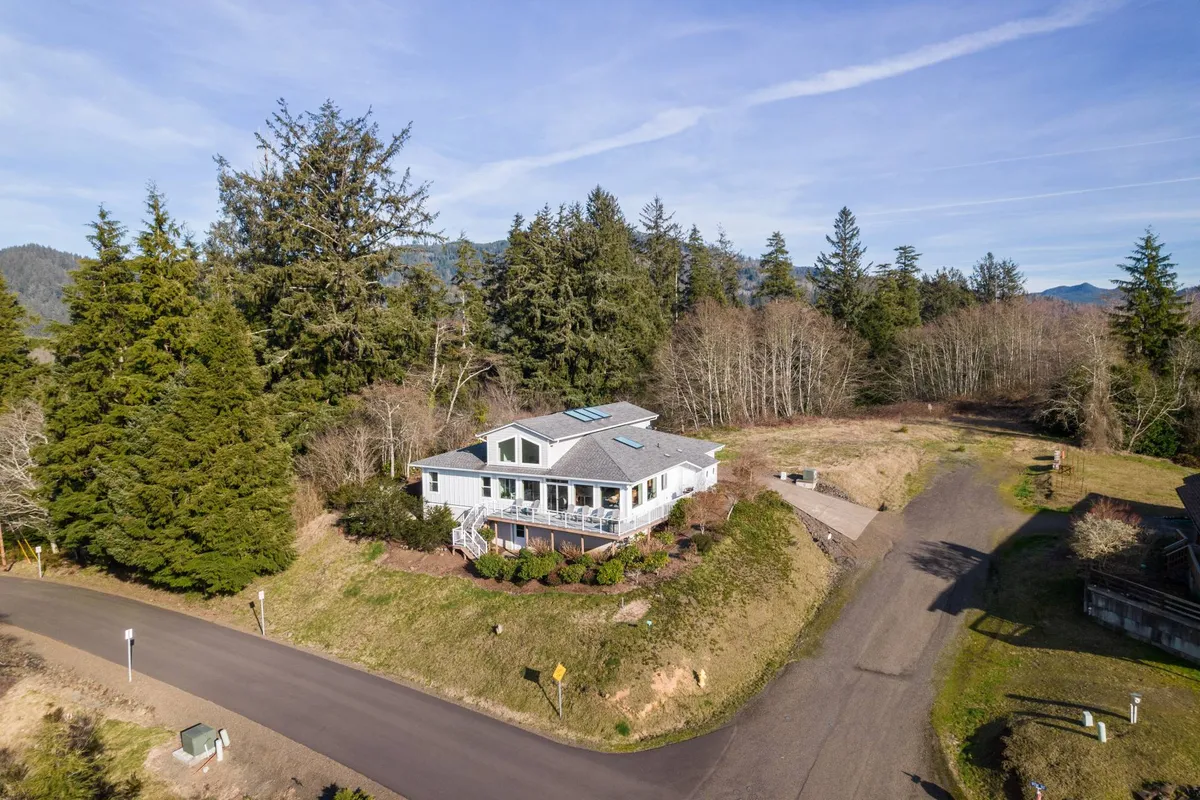 A peaceful exterior shot of the villa nestled among trees, with a view of the porch and surrounding landscape. The scene suggests a quiet, natural setting perfect for relaxing, taking in seasonal changes, or enjoying a starry night.